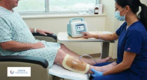 Nurse applying Negative Pressure Wound Therapy (NPWT) to a patient's leg using a wound vacuum device in a clinical setting at the Centre for Advanced Wound Care.